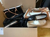Box containing several ladies faux leather handbags and shoes in various colors and styles, some with handles wrapped in plastic.