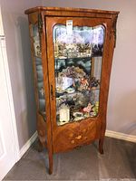 Full front view of cabinet showing glass door, tufted back and marquetry inlay