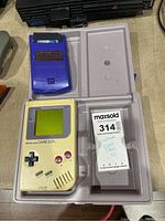 Nintendo Game Boy DMG-01 and Game Boy Color with game cartridge and carrying case displayed in plastic tray