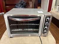 Front view of the stainless steel KitchenAid toaster oven with chromed handle and glass door.