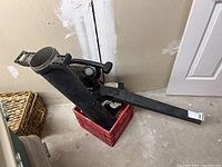 Black Toro Rake & Vac leaf blower with attached long blower tube and narrow nozzle sitting on a crate.