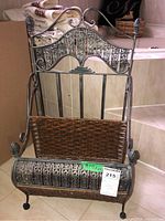 Front view of metal and wicker rack showing intricate metal scrollwork and wicker seating surface