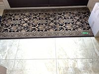 Rectangular acrylic rug laid flat near a doorway, showing full length and detailed pattern.