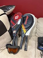 Three tennis racquets including Wilson Titania cover, Mizuno and Prince covers, plus ski goggles with brown lenses.