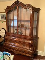 Full view of vintage china cabinet showing glass doors, inlaid decoration and bombe lower drawers