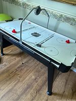 Full view of the NHL air hockey table showing playing surface, table legs, and side branding.