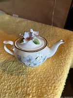 Royal Stratford Queen Anne bone china teapot with floral design sitting on a yellow textured surface