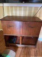 Front view of wooden cabinet with two doors and lower shelf, showing some scratches on wood surface.