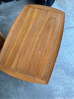 Top view of one end table showing walnut wood surface with some scratches and smooth finish.