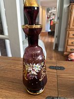 Front view of the decanter showing the hand-painted white flowers and gold accents.