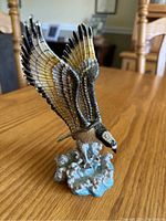 Photo showing eagle figurine mid-flight with detailed wings and base simulating water splash.