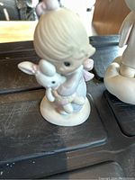 Porcelain child figurine holding a white bunny on a round base.