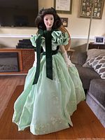 Front view of the Franklin Heirloom doll Scarlet O'Hara in pale green floral dress with black velvet ribbons and straw hat.