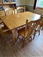 Harvest table with 6 solid oak dining chairs around it, clear view of table surface and chair design.