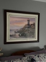 Framed lighthouse picture showing the full piece mounted on wall above a bed headboard.