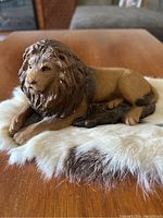 Front angle of Resting Lion figurine with detailed mane and tan body on fur-like base