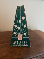 Original Wittner Metronom box, green with white geometric design and logo, marked "System Maizel Nr."