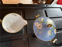 Milk pitcher and sugar bowl with lid shown side by side on a dark surface, highlighting blue crackle glaze and floral design with gold accents.