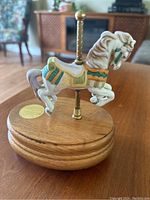 Front side view showing the horse figurine and detailed paint work on the saddle and mane, mounted on a wooden base with a gold-tone sticker.