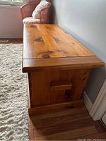 Side view of the pine blanket box showing panel side and visible wood knots.