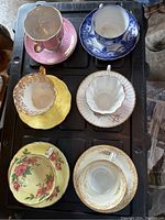 Top-down view of all six teacups with saucers showing varied colors and patterns.