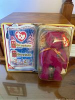 Front view of Ty Millennium bear in original blister packaging, showing bear, Ty logo, and certificate.