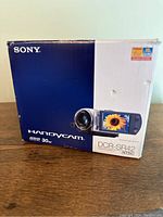 Original Sony Handycam DCR-SR42 box showing branding, model number, HDD 30GB capacity, and product image with LCD screen displaying a sunflower.