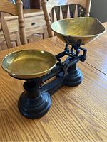 Front-side angle of the vintage balance scale showing brass pans and cast iron base.