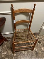 Front view of the wooden ladder back chair showing the overall chair design and woven seat