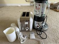 Photo showing all three appliances: blender, toaster, hand mixer, and mixing cup on carpeted floor.
