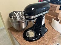 Black KitchenAid Classic mixer with stainless bowls and attachments on countertop
