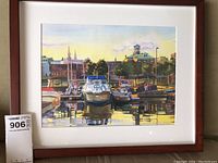 Frontal image of the artwork in wooden frame showing the watercolor painting of boats docked at Brockville waterfront with reflected water and buildings in the background under a soft sky.