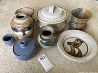 Collection of seven pottery pieces including vases, covered pot, plate, and bowls showing various styles and glazes.