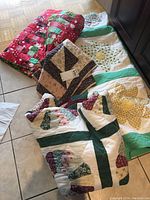 Overview of multiple folded quilts and shams with various patchwork designs placed on floor tiles