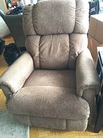 Front view of a brown fabric recliner chair showing cushioned wide seat and padded backrest.