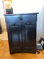 Front view showing drawer and two paneled doors with knobs, revealing cabinet condition and design.