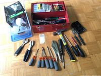Overview photo of tools laid out beside the small red metal tool box and plastic boxes with lighting bulbs