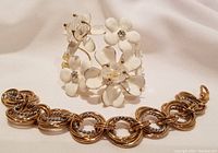 Both bracelets shown together, displaying size and style contrast between floral cuff and linked bracelet