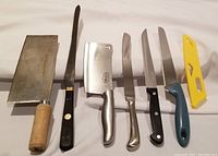 Full set of 6 cutting utensils and cleavers displayed on a white cloth with blades and handles visible