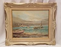 Full view of the framed oil painting showing boats on water, figures rowing, cloudy sky, and detailed ornate cream-colored frame.
