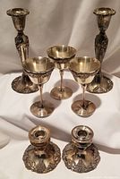 Front view of two wine goblets and two smaller candlesticks with grapevine design on base and stem, showing details and condition.