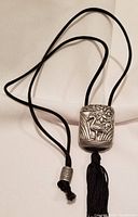 Full view of the snuff medicine box pendant hanging on the black silk cord with slider bead knot detail.