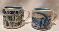 Both mugs side by side showing full designs of Niagara Falls and Michigan