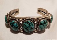 Frontal view showing five oval turquoise stones in rope bezel setting on sterling silver cuff.