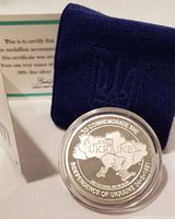 Medallion in plastic capsule alongside certificate and navy felt holder