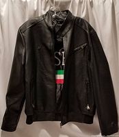 Full front view of black faux leather jacket on hanger showing zip pockets and collar