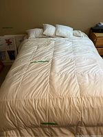 Photo showing the double bed fully made with white duvet and multiple white pillows arranged on top.
