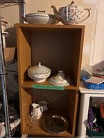 Photo showing the floral teapot on top, covered dishes in the middle, and Sherry glasses and Audubon bird plates on the bottom shelf