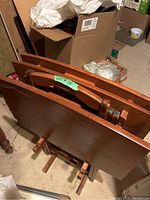 Photo showing the four folding wooden tables stacked together folded, with a green label Lot #130.