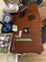 Wooden expandable side table top view with several small items on it, showing the shape and finish of the wood surface.